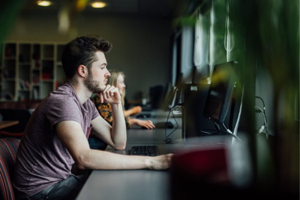 student in library typing on a PC