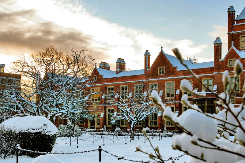 View of the red-bricked Physics building from the quad in the snow against a bright sky