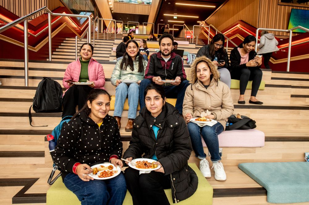 students sitting on One Elmwood staircase eating food