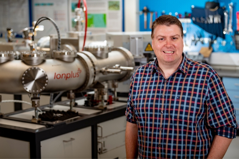 Professor Graeme Swindles standing the radiocarbon accelerator in the 14CHRONO lab at Queen's University Belfast