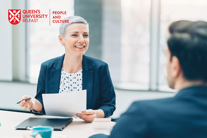 Queen's University Belfast People and Culture Directorate - image shows young professional woman smiling at man in workplace