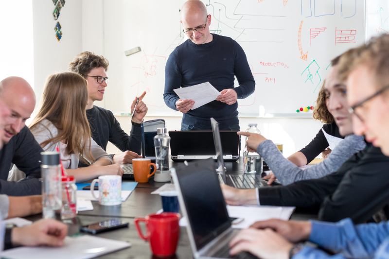 A group pictured sitting around a desk in an office during a team meeting