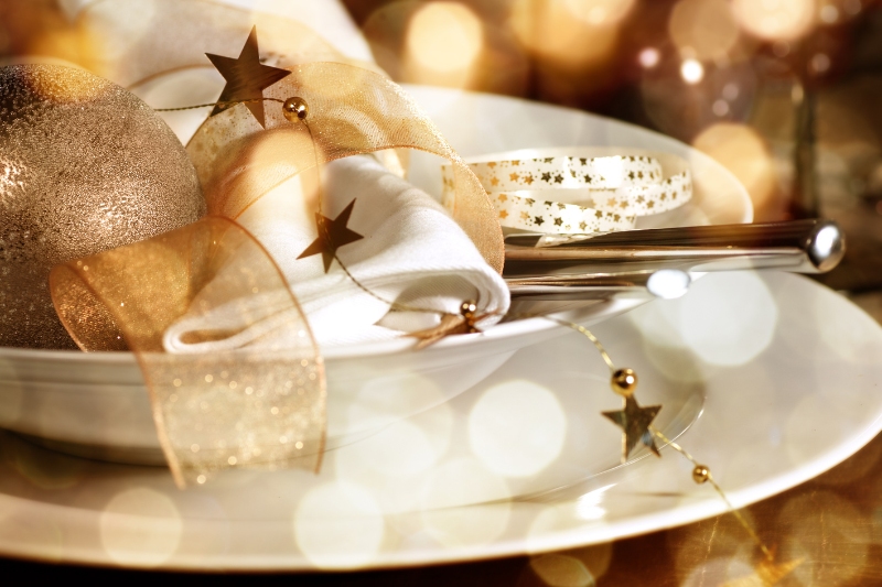 Christmas decorative items sitting on top of white crockery and cutlery in a cosy dinner setting