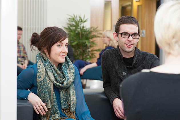 a male and female student listening to another student talking