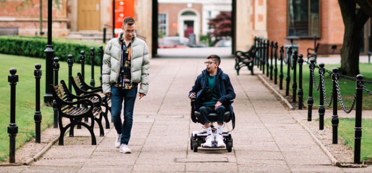 Two male students, one a wheelchair user, chatting and moving through the quadrangle, Queen's University Belfast