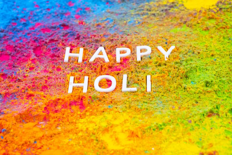 capital letter shapes forming the words 'Happy Holi' set onto dry paint powders