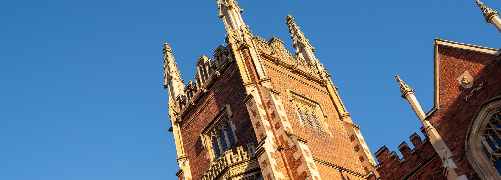 sunlight on a Gothic-style tower and turret with blue sky in the background