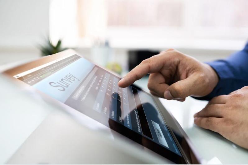 A man's hand completing an online survey on a laptop.