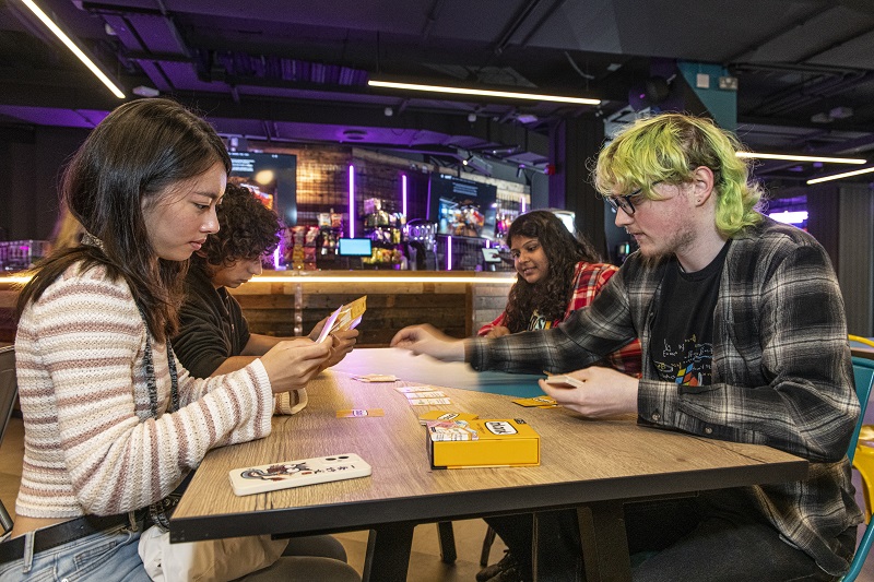 students gaming in the bright, vibrant, neon Reboot cafe and gaming hub, Lisburn Road