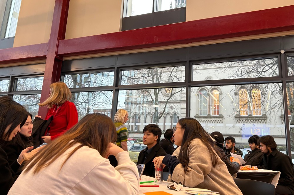 international students seated at a table and chatting at an indoor event
